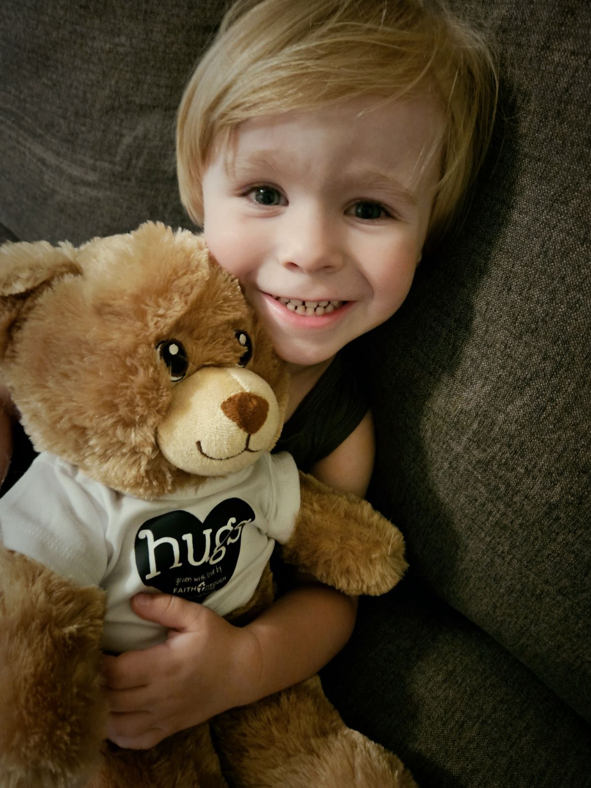 Child holding a Faith Through Fire Bear Hugs teddy bear